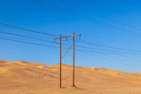 Pilone Elettrico Nel Deserto Con Pila Legno Sotto Cielo Blu — Foto Stock
