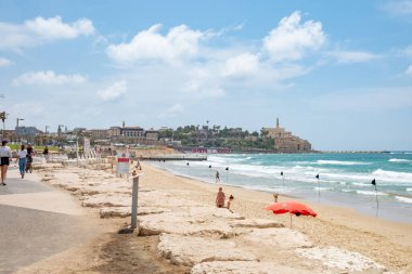 Tel Aviv, İsrail - 18 Mayıs 2023: insanlar Tel Aviv 'deki güzel kumlu plajın tadını çıkarıyorlar. Arka planda eski Tel Aviv kasabası.