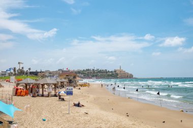 Tel Aviv, İsrail - 18 Mayıs 2023: insanlar Tel Aviv 'deki güzel kumlu plajın tadını çıkarıyorlar. Arka planda eski Tel Aviv kasabası.