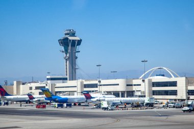 Los Angeles, ABD - 29 Haziran 2012: Araçlar ve yükleyiciler bir sonraki uçağı boşaltmaya hazır, Farklı Havayolları uçakları terminalin kapısında hazır bekliyor..