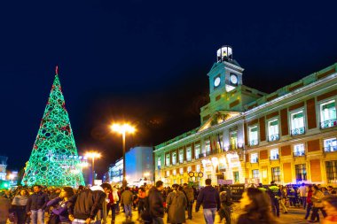 Madrid, İspanya - 22 Aralık 2010: İnsanlar İspanya 'nın Madrid kentindeki Puerta del Sol' da noel ağacının önünden geçerken eğleniyorlar.