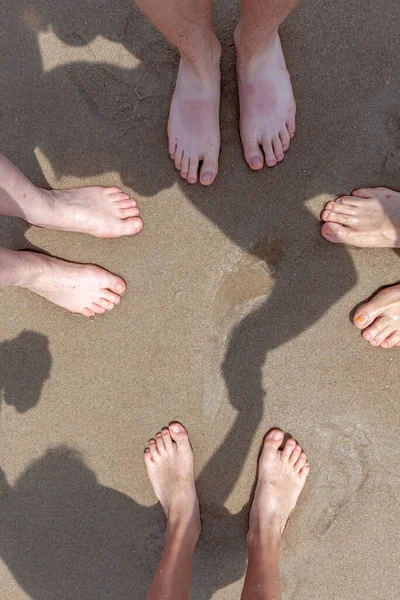 feet of family at the sandy beach