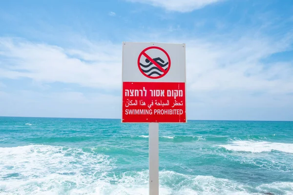 stock image swimming forbidden in english and hebrew at a sign at the beach in Tel Aviv, Israel