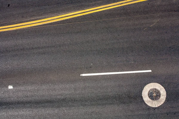 以黄色中位数为交通标志的灰色街道上的沟渠 — 图库照片