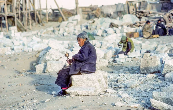 1987年4月19日 丘からの老婦人の肖像画ラサ 中国での祈りのホイールを使用して ジョカン チベットでの新しい建物の建設現場に座って — ストック写真
