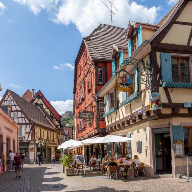 Ribeauville, Fransa - 23 Haziran 2023: Ribeauville, Alsace bölgesindeki Ribeauville köyünde yarım ahşap binalar ve kafeler bulunan pitoresk renkli bir sokak.