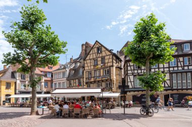 Colmar, Fransa - 21 Haziran 2023: Fransa 'nın Colmar kentindeki Dominik meydanı, yarı keresteli evler ve turistlerle birlikte, bir yaz günü kafelerde oturmanın keyfini çıkarıyorlar..