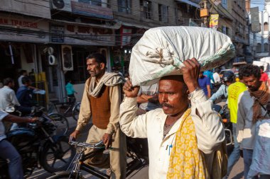 Yeni Delhi, Hindistan - 17 Kasım 2011: Eski Delhi 'deki en eski Chandni Chowk pazarında sokak hayatı. Chandni Chowk 'taki Meena Çarşısı' nda kafasında mal taşıyan insanlar.