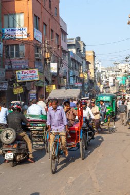 Yeni Delhi, Hindistan - 17 Kasım 2011: Eski Delhi 'deki en eski Chandni Chowk pazarında sokak hayatı. Çekçek şoförü, bisikletli triportörüyle yolcu taşıyor..