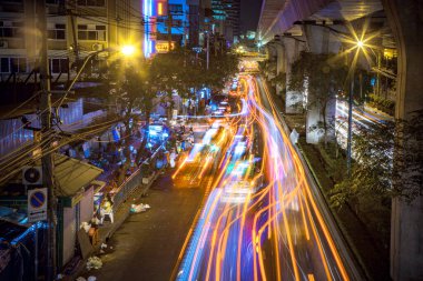 Bangkok, Tayland - 21 Aralık 2009: Sukhumvit yolundaki arabalar gece durur ve uzun pozlama efektiyle giderler.