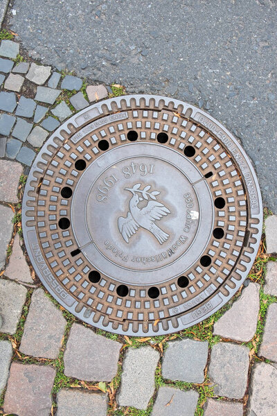 Muenster, Germany - August 5, 2023: water drain with inscription Westphalian peace - german :westpfaelischer frieden to honor the historic peace agreement in Muenster.