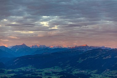 Gündoğumu Gruenten 'in dağlık tepesinden Rettenberg köyü ve Almanya' nın Alpler panoramasıyla görüldü.