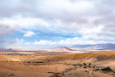 Fuerteventura adasındaki manzara bulutlu gökyüzünün altındaki dağlara bakıyor.