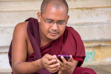 Pagan, Myanmar - 14 Ağustos 2015: Geleneksel elbiseli keşiş iletişim kurmak için cep telefonu kullanıyor.
