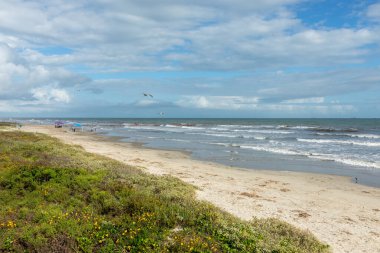 İnsanlar Meksika körfezindeki güzel kumlu plajın tadını çıkarıyorlar Galveston adasında Teksas, ABD 'de dramatik bir şekilde güzel bir gökyüzü var..