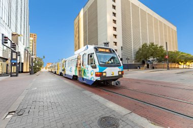 Dallas, ABD - 6 Kasım 2023: Dallas şehir merkezinde bir tramvay, üzerinde mutlu genç bir kız resmi olan bir reklam aracı..