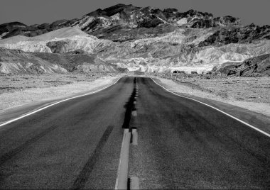 Çöldeki vadide, arkasında dağlar olan bir yol.