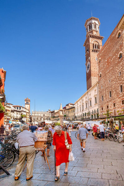 Verona, Italy - August 5, 2009:  People walking at Piazza delle Erbe - Market's square. This is a oldest square of Verona with famous Lamberti Tower.