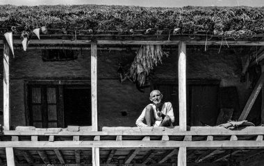 Helambu, Nepal - 30 Haziran 1981: Ahşap çiftlik evinde piposunu tüttüren yaşlı bir çiftçi.