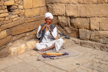 Jaisalmer, Hindistan - 13 Şubat 2024: Jaisalmer Kalesi, Rajasthan, Hindistan 'da sadaka dilenen yaşlı adam flüt çalıyor.