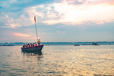 Varanasi, Hindistan - 24 Şubat 2024: Ganj nehrindeki eski ahşap botlar sabah vakti Hinduist insanların yanan kültünü izleyen insanlarla birlikte.