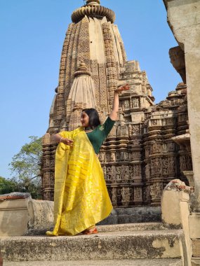 Raknapur, India - March 1, 2024: woman poses in front of the Jain Ranakpur Temple in Pali, Rajasthan.  This temple is famous for erotic practices on the panels of temple walls. clipart