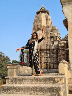 Raknapur, India - March 1, 2024: woman poses in front of the Jain Ranakpur Temple in Pali, Rajasthan.  This temple is famous for experimental love making scenes and erotic practices on the panels of temple walls. clipart