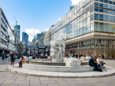 Frankfurt, Almanya - 10 Nisan 2024: İnsanlar Frankfurt 'ta yaya bölgesinde yürüyorlar. Zeil, 1985' ten sanatçı Lutz Brockhaus 'un mermer çeşmesiyle..