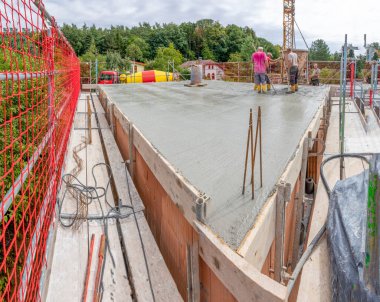 Fischbach, Almanya - 25 Ağustos 2020: inşaat alanında beton karıştırıcı ve darağacına sahip bir aile evinin temelini döken işçiler.