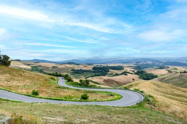 Volterra yakınlarındaki manzaralı tepe. Kavisli cadde ve mavi gökyüzü Toskana, İtalya 'da.