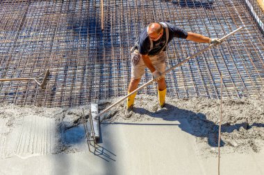 Fischbach, Almanya - 23 Temmuz 2020: demir çubuğu beton temel için hazırlayan ve çubuk inşaatını beton karıştırıcıdan taze betonla dolduran işçi, .