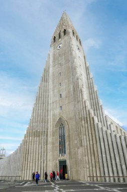 Reykjavik, İzlanda - 13 Temmuz 2023: Güzel Hallgrimskirkja kilisesi ve Reykjavik şehir merkezindeki kaşif heykeli. Gün batımında bulutlu gökyüzüne karşı en uzun katedralin önünde çimenler büyüyor..