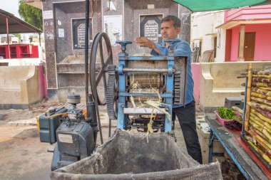 Deshnoke, Hindistan - 12 Şubat 2024: bambu makinesindeki adam Hintli turistlere taze bambu suyu satıyor.