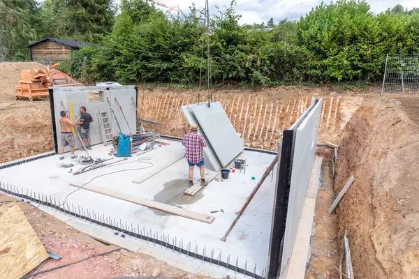 stock image Fischbach, Germany - July 28, 2020: worker at the construction site prepare with prefabricated walls the cellar with waterproof concrete called white cellar construction.