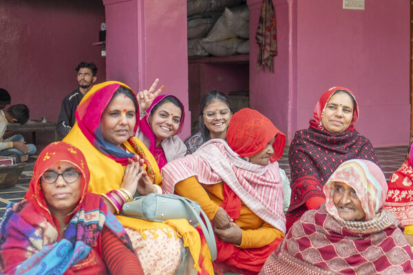 Deshnoke, India - February 12, 2024: attractive indian women in traditional clothes sitting at the steps of the Deshnoke temple and having fun by talking and resting.