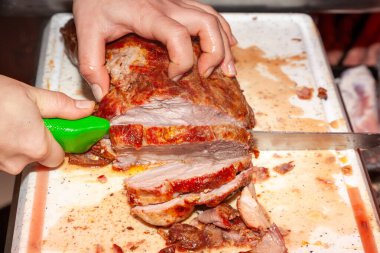 Kasap keskin bir bıçakla sıcak rostoyu dilimler halinde kesiyor.