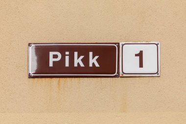 old brown enamel streetname Pikk 1 in Tallinn, Estonia at an old wall in the old town clipart