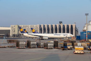 Hamburg, Almanya - 19 Mart 2015: aprondaki konteynır Lufthansa uçağının arka plandaki terminalinde ve Lufthansa uçaklarında beklemede..