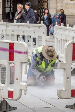 Münih, Almanya - 26 Ekim 2016: Münih 'te Marienplatz' da turistlerle fayansları kesen makineli işçi.