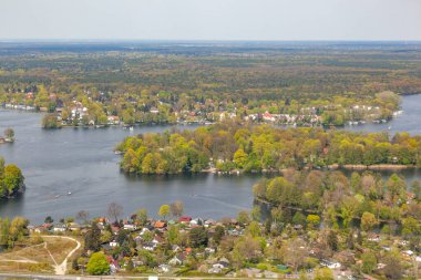 Berlin 'deki Wannsee' nin manzaralı havasında ağaçlar ve gölde tekneler olan yeşil alanda villalar var.