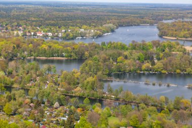Berlin 'deki Wannsee' nin manzaralı havasında ağaçlar ve gölde tekneler olan yeşil alanda villalar var.