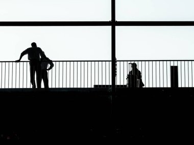 Üst katta tren istasyonunu bekleyen insanların silueti.