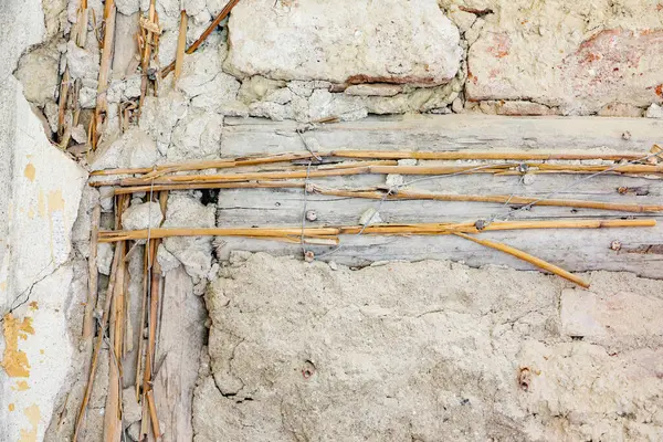 Hasarlı eski ringa kemiği parketinin arka planı. Hasarlı durumdaki tarihi duvarın ayrıntıları. Tahtaya saman çivilenmiş ve duvarda kırık alçı var.