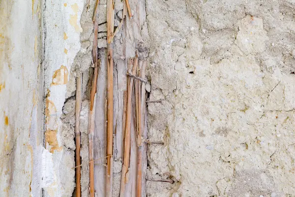 Hasarlı eski ringa kemiği parketinin arka planı. Hasarlı durumdaki tarihi duvarın ayrıntıları. Tahtaya saman çivilenmiş ve duvarda kırık alçı var.