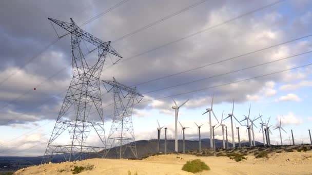 Eine Gruppe Von Windkraftanlagen Neben Zwei Großen Stromtürmen Die Eine — Stockvideo