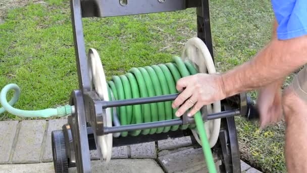 一个在院子里干活的人完成了他的浇水任务 把花园的软管卷进了储物车 — 图库视频影像