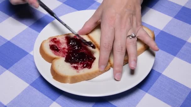 女性は新鮮な白パンに古典的なピーナッツバターとゼリーサンドイッチを作ります — ストック動画