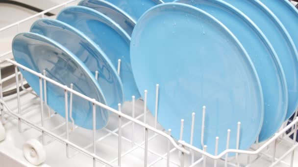 夕食後 人は掃除する家庭用食器洗い機器具に青 汚れた料理をロードします — ストック動画
