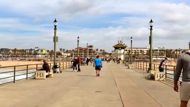 観光客は美しい夏の日にハンティントンビーチの桟橋を群がり 地元の食べ物で素晴らしいビーチや食事を見ることができます — ストック動画