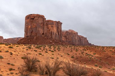 Large mountain along the side of Monument Valley's scenic park during a cloudy day shows the rock patterns, generally made of sandstone, moenkopi and or shinarump rock. clipart